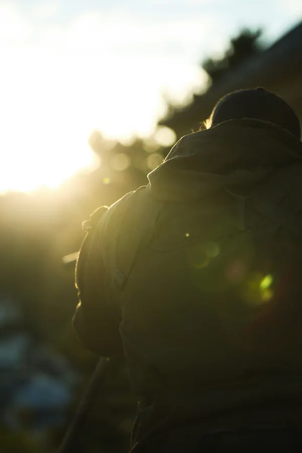 Backlit figure at last light, sun breaking over the ridge