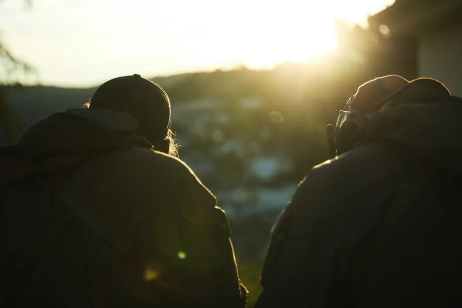 Two operators looking out over the valley as the sun drops behind the ridge