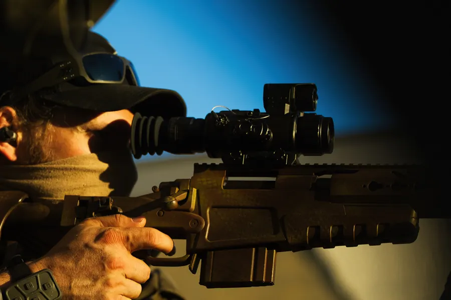 Marksman in profile against open sky, rifle supported on the bipod