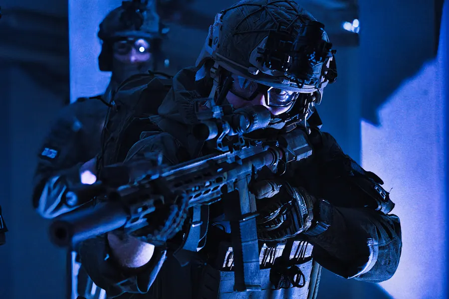 Operator advancing in blue night light, rifle shouldered