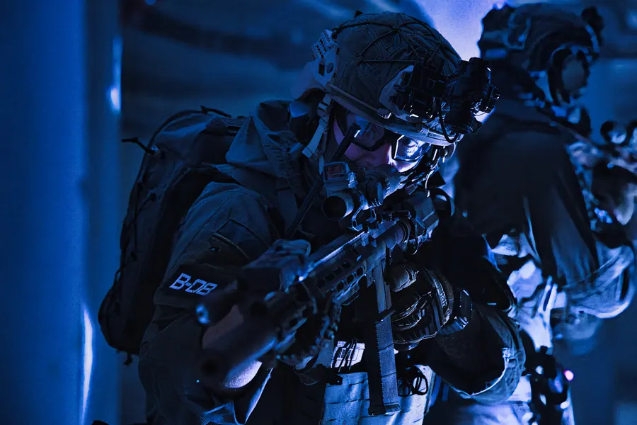 Operator advancing through a room under night light, rifle up