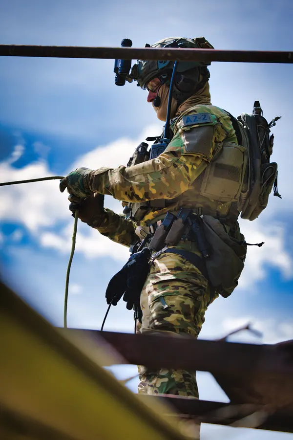 Operator on a rope against open sky, kit and helmet in profile