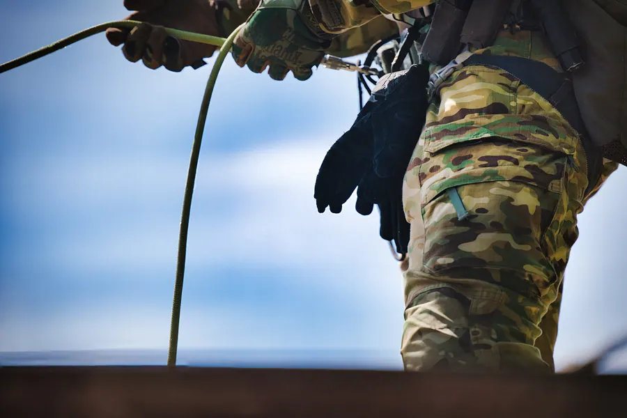 Gloved hand feeding rope at the hip, sky behind