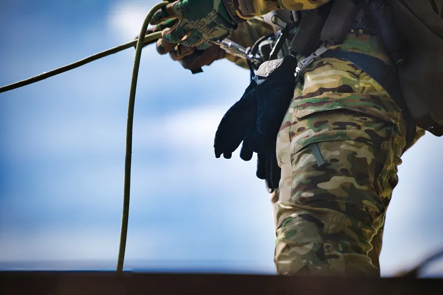 Rope running through a gloved hand, kit and trousers in frame