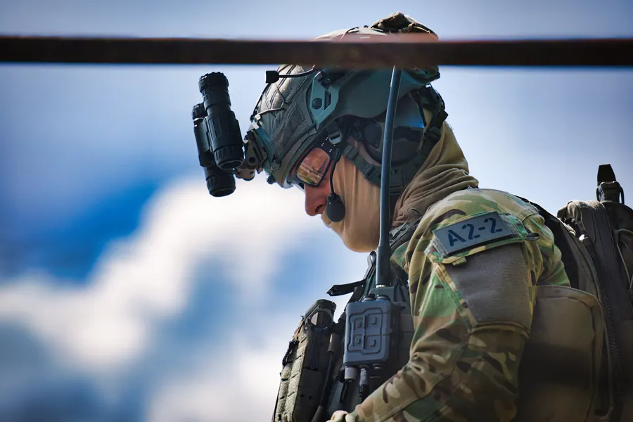 Operator in profile against cloud, helmet, night vision mount and radio