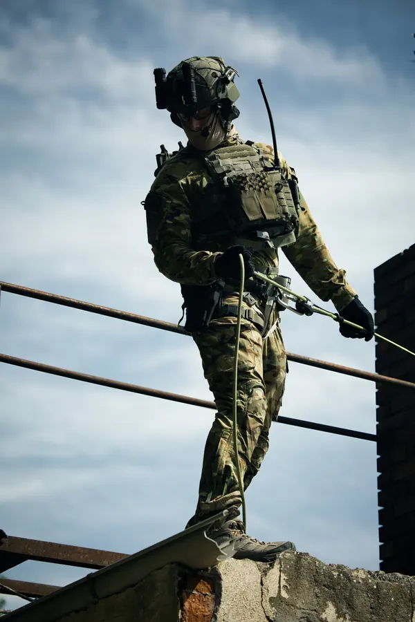 Operator on a rooftop edge against open sky, rope in hand