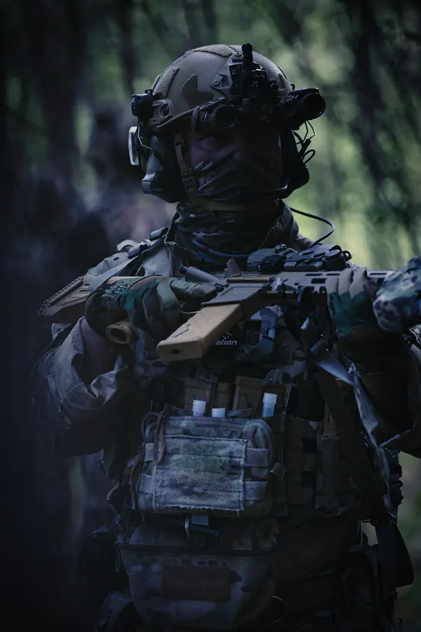 Operator facing camera in dark woodland, carrier and pouches in front
