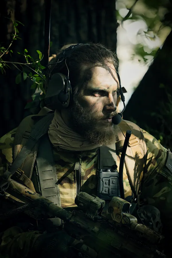 Bearded operator in woodland, headset and radio antenna at the shoulder