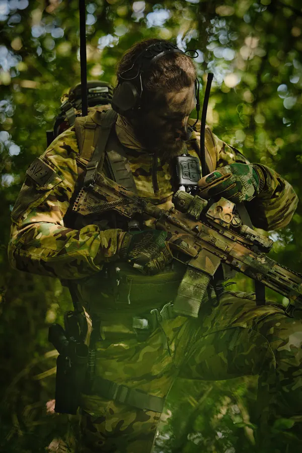 Operator standing in bright foliage, carrier and radio antenna visible