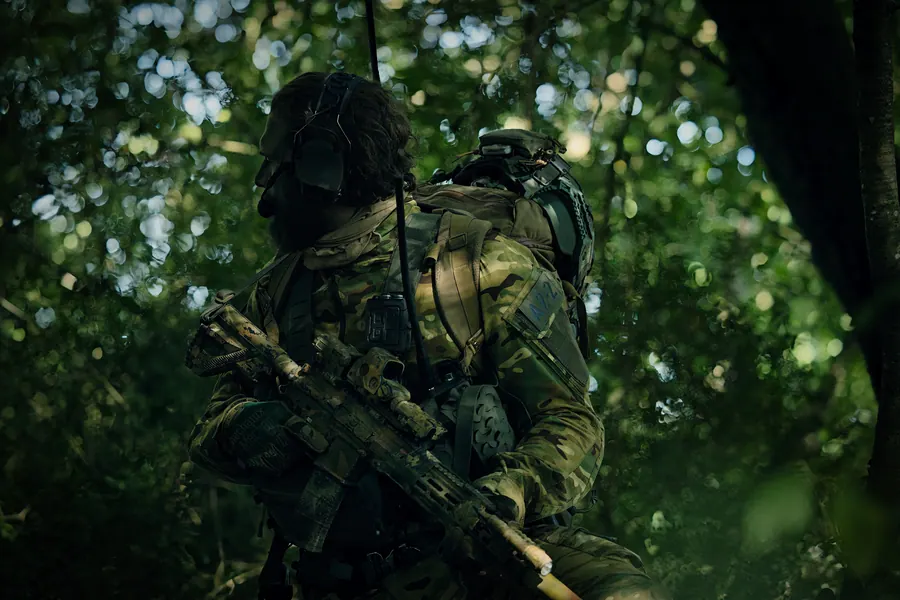 Operator moving through dense green undergrowth, kit under load