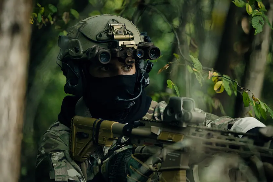 Portrait in woodland behind foliage, helmet with quad tube night vision