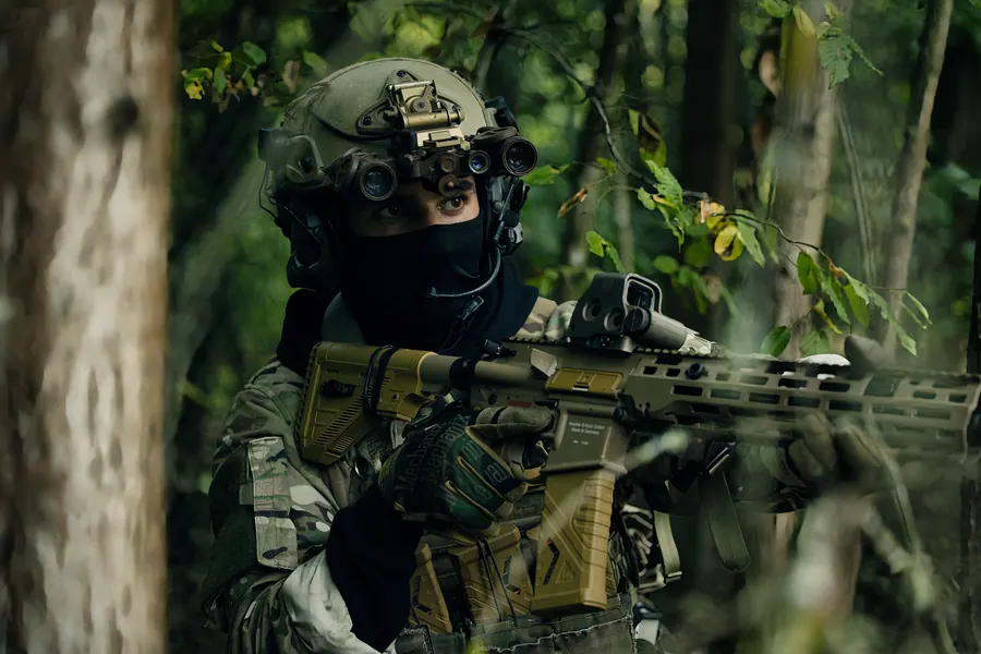 Operator scanning through woodland, night vision device on the helmet