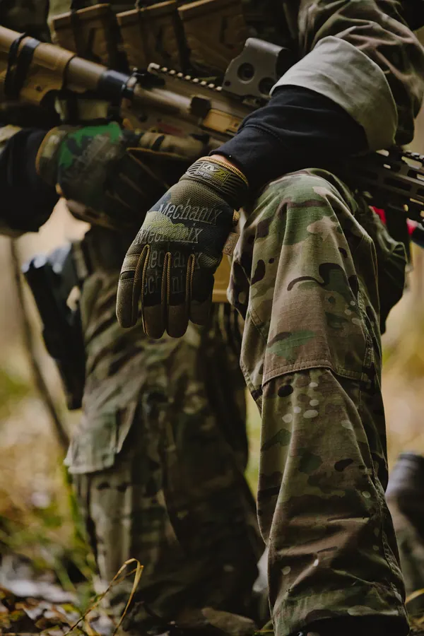 Torso and gloved hand on the carrier front, woodland behind